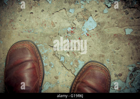 vintage worn-out boots on concrete floor, closeup Stock Photo