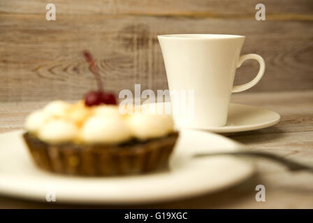 Cake with a cherry and white cup on the table Stock Photo
