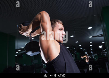 Side view of athletic man doing triceps exercise with dumbbell Stock Photo