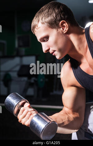 Close-up of young man doing concentration curls with dumbbell Stock Photo