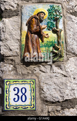 Traditional ceramic house number and monk image outside a walled garden in Capri Stock Photo