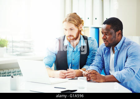 Two businessmen or designers discussing new project in front of laptop Stock Photo