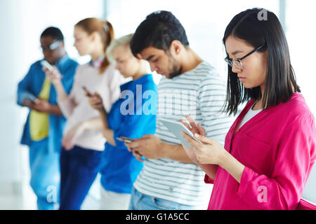 Group of contemporary multi-ethnic students using gadgets Stock Photo