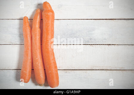 Some carrots on a white wooden table in a rustic kitchen. Empty copy space for editor's text. Stock Photo