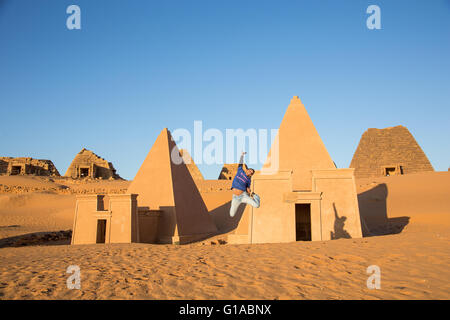 a young man jumping in front on Meroe pyramids in Sudan Stock Photo