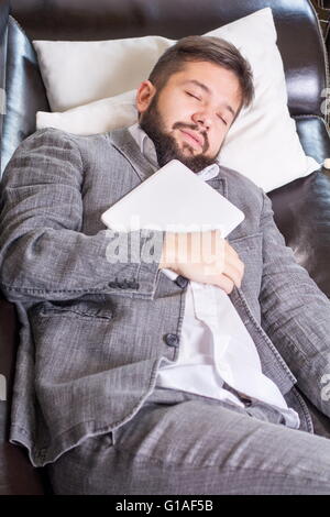 Sleepy businessman with a tablet device on a  sofa Stock Photo