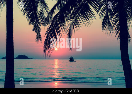 Beautiful bloody sunset on a tropical beach, palm trees silhouettes. Stock Photo