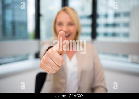 Happy Business woman thumbs up. Modern office background. Face camera Stock Photo