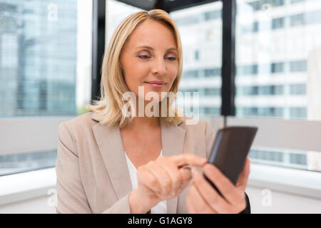 Middle aged business woman working at office. Using smartphone Stock Photo