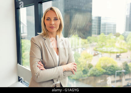 Portrait of businesswoman in modern office. Building in background. Face camera Stock Photo