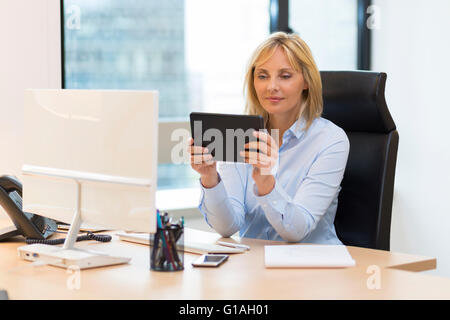 Middle aged business woman using digital tablet at office Stock Photo