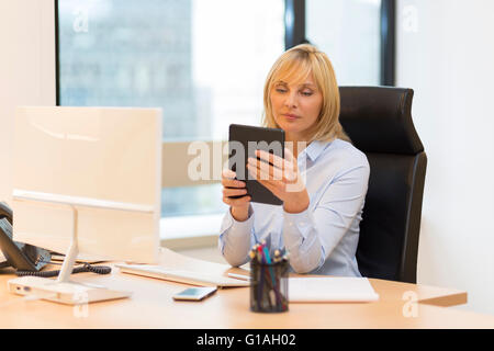 Middle aged business woman using tablet pc at office Stock Photo
