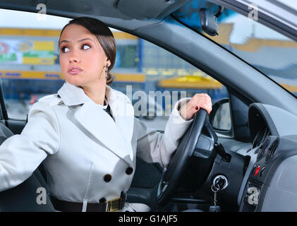 woman in a car is looking backwards trying to move back Stock Photo