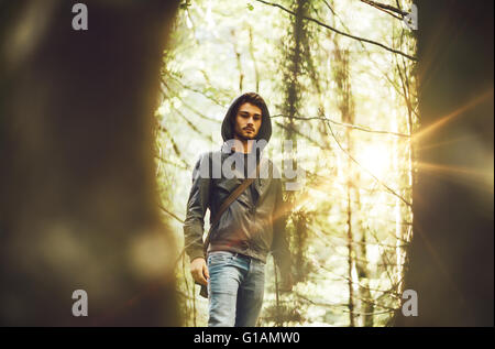 Young man walking in the forest framed by trees Stock Photo