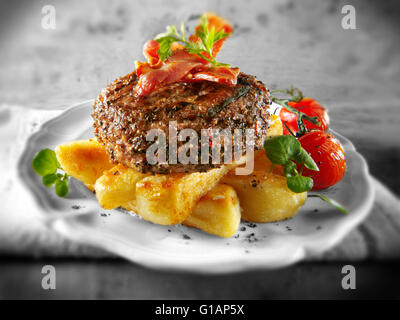 Cooked Peppered beef burger or hamburger with bacon and chunky chips Stock Photo