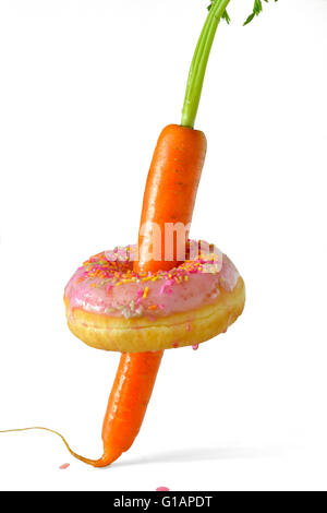 Whole raw carrot spears through a ring doughnut with pink icing and sprinkles. Stock Photo