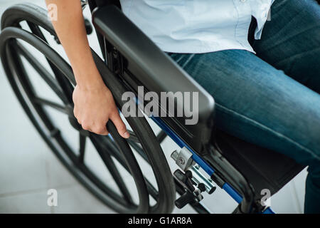 Woman in wheelchair's hand on wheel close up, disability and handicap concept Stock Photo