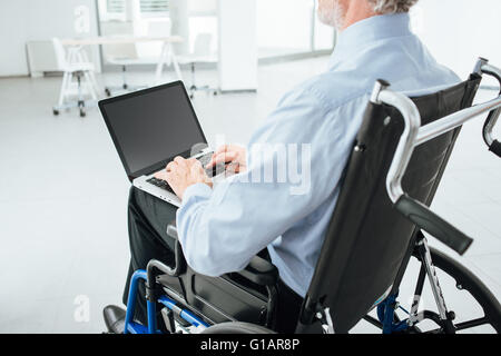 Corporate businessman in wheelchair using a laptop and networking, unrecognizable person Stock Photo