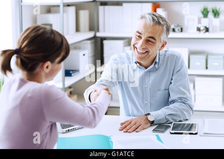 Happy young candidate shaking hands with her employer after a job interview, employment and business meetings concept Stock Photo