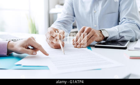 Business people negotiating a contract, they are pointing on a document and discussing together Stock Photo