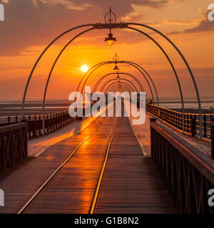 Southport, Merseyside, UK. 12th May, 2016. UK Weather: Sunset over the pier at Southport after a day of startling temperatures in the north-west of England with 25c being recorded in some areas.  At this time of the year the sun sets almost at the end of the pier giving a perception of the tram lines leading to infinity. Credit:  Mar Photographics/Alamy Live News Stock Photo