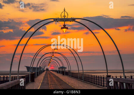 Southport, Merseyside, UK. 12th May, 2016. UK Weather: Sunset over the pier at Southport after a day of startling temperatures in the north-west of England with 25c being recorded in some areas.  At this time of the year the sun sets almost at the end of the pier giving a perception of the tram lines leading to infinity. Credit:  Mar Photographics/Alamy Live News Stock Photo