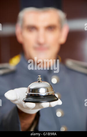 Concierge holding hotel bell on his hand with gloves Stock Photo