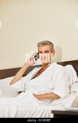 Elderly man using his smartphone to make a phone call in a hotel room Stock Photo