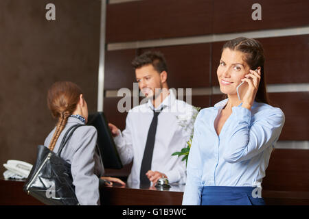 Friendly concierge serving hotel guests at reception Stock Photo