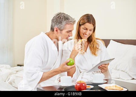 Couple with tablet computer having breakfast in a hotel room Stock Photo