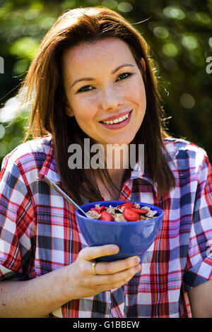 Portrait of a Woman Eating Breakfast Cereals With Fruit Outside in the Garden Looking Happy and Relaxed Stock Photo