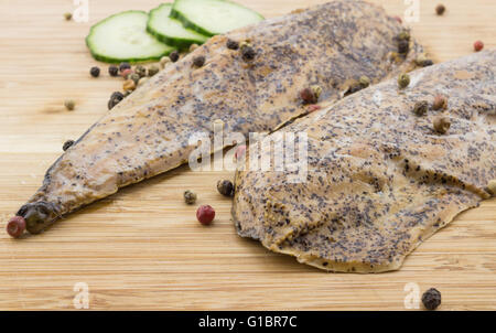 Two smoked mackerel fish close up on wood with cucumber slices Stock Photo