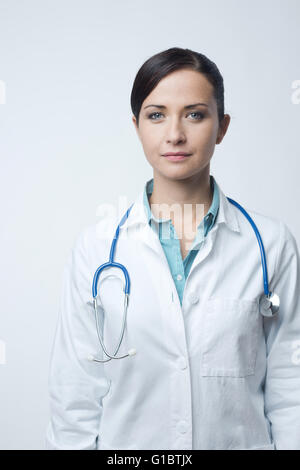 Confident smiling female doctor posing with lab coat and stethoscope. Stock Photo