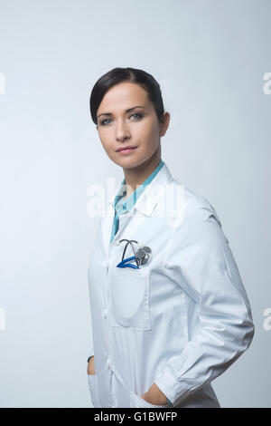 Confident smiling female doctor posing with lab coat and stethoscope. Stock Photo