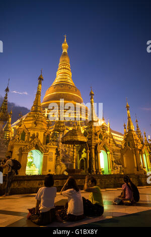 People meditating at the Shwedagon Paya in Yangon during sunset Stock Photo