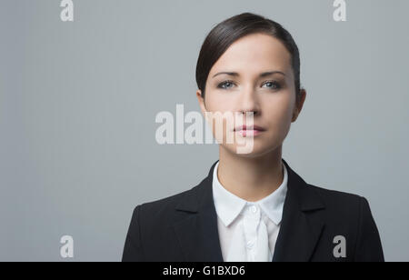 Serious confident businesswoman staring at camera and posing on gray background. Stock Photo