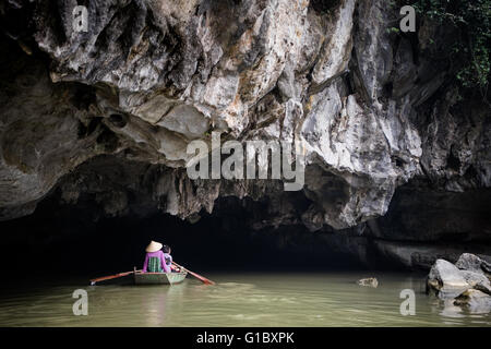 People making their way by rowing boat into a cave in Ninh Binh Province, Vietnam Stock Photo