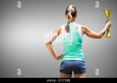 Composite image of rear view of sporty woman holding olympic torch Stock Photo