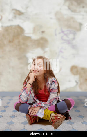 a young teenager sitting cross-legged on the floor Stock Photo