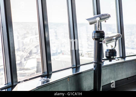 Telescopes overlooking a city on an observation deck at a high tower Stock Photo