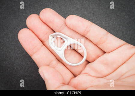 Woman hand holding ring pull cans opener on black metallic background Stock Photo