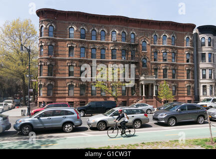 Man cycling along Prospect Park West cycle path with apartment building in background, Brooklyn, New York, USA Stock Photo