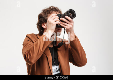 Man with curly hair photographing something on camera isolated on a white background Stock Photo