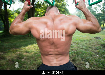 Close-Up Muscular Built Young Athlete Working Out In An Outdoor Gym - Doing Chin-Ups Stock Photo