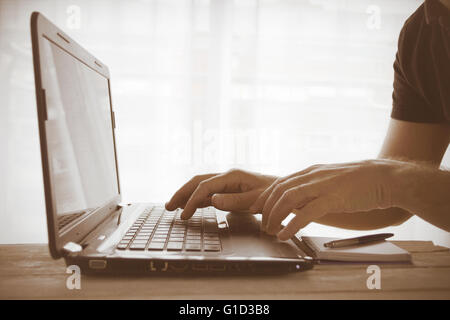 Man using a laptop and taking notes against a window. Empty copy space for Editor's text. Stock Photo
