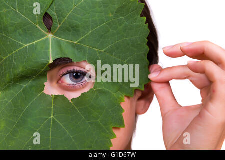 Green tree leaf with a female eye peeping through Stock Photo