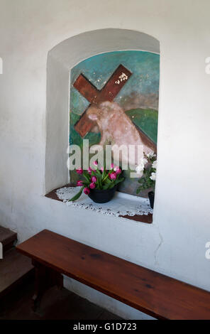 Jesus falling down with cross on his back, painting in niche on the wall in the covered stairs way leading to Franciscan Church. Stock Photo