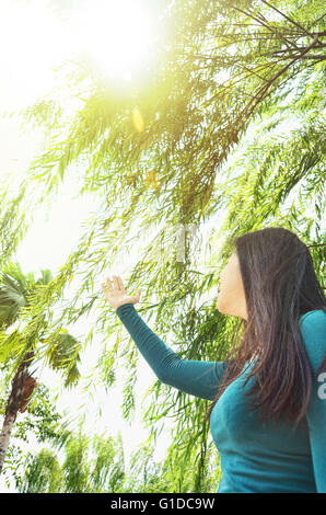 Girl rising her hand to touch leaves Stock Photo