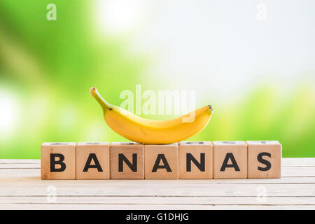 Banana sign with a yellow banana on top on a wooden desk Stock Photo