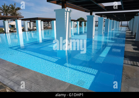 HERAKLION, CRETE, GREECE - MAY 13, 2014: Blue swimming-pool, modern building with columns, beach in popular luxury class hotel Stock Photo